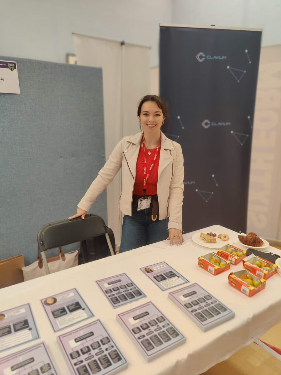 Lucy standing behind a stand with handouts at a Girls in Tech day
